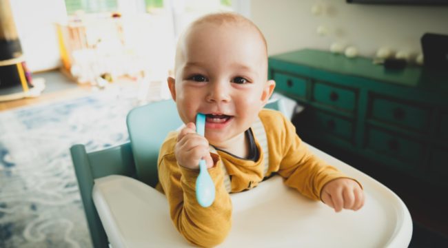 Toddler smiles and looks happy on wooden high chairs