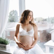 pregnant woman in white underwear sits and looks in window