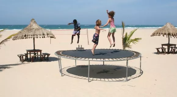 three children on trampoline on beach
