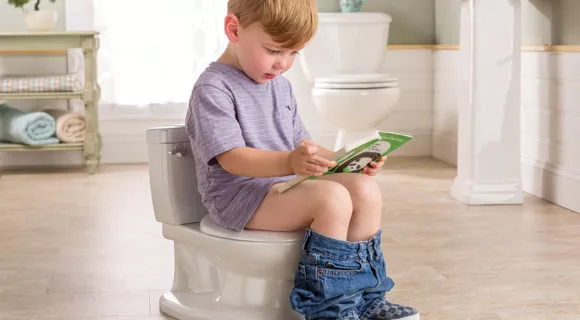 A little boy sits on potty and reads a book